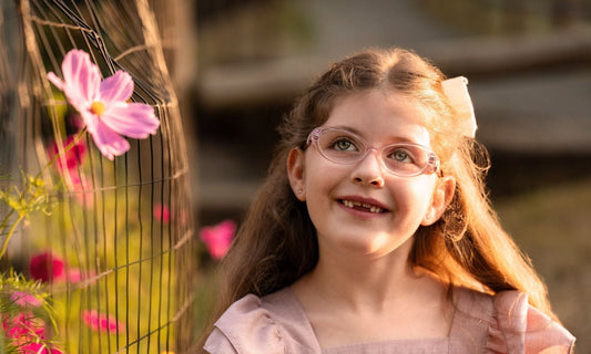 Girl wearing Once Upon a Charm Glasses looking at a flower