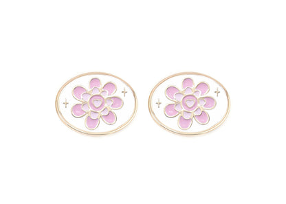 Pair of floral earrings with pink centers and gold accents on a white background